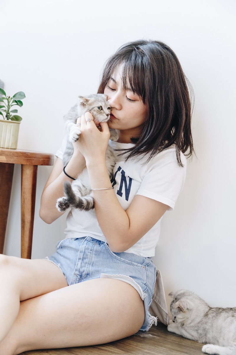 woman sitting and kissing kitten